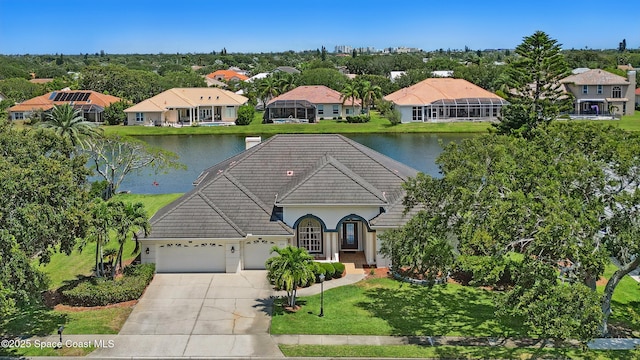 view of front of property featuring an attached garage, concrete driveway, a tiled roof, a water view, and a residential view