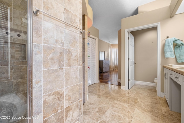 bathroom featuring toilet, vanity, and a tile shower