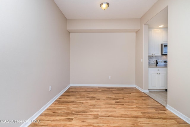 unfurnished room featuring baseboards, recessed lighting, and light wood-style floors