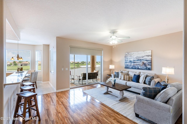6838 Toland Dr Unit 307, Melbourne, FL 32940 - living room featuring a ceiling fan, light wood-style floors, baseboards, a textured ceiling, and a water view