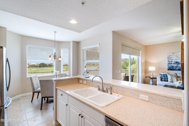 6838 Toland Dr Unit 307, Melbourne, FL 32940 - kitchen featuring a sink, freestanding refrigerator, white cabinets, decorative light fixtures, and light countertops