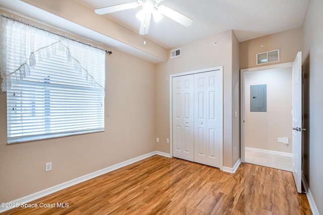 6838 Toland Dr Unit 307, Melbourne, FL 32940 - unfurnished bedroom featuring electric panel, light wood-style flooring, a closet, baseboards, and ceiling fan