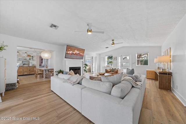 216 Cynthia Ln, Indian Harbour Beach, FL 32937 - living area with a fireplace, a ceiling fan, visible vents, wood finished floors, and lofted ceiling