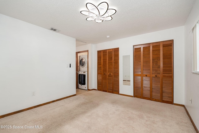 3021 Kirkland Rd NE, Palm Bay, FL 32905 - unfurnished bedroom featuring multiple closets, stacked washer / drying machine, carpet floors, and visible vents