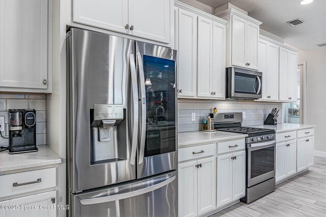 7921 Mocan Ct, Melbourne, FL 32940 - kitchen with stainless steel appliances, backsplash, light countertops, white cabinetry, and recessed lighting