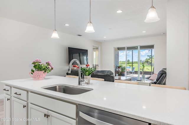 7921 Mocan Ct, Melbourne, FL 32940 - kitchen featuring stainless steel dishwasher, a sink, open floor plan, decorative light fixtures, and white cabinets