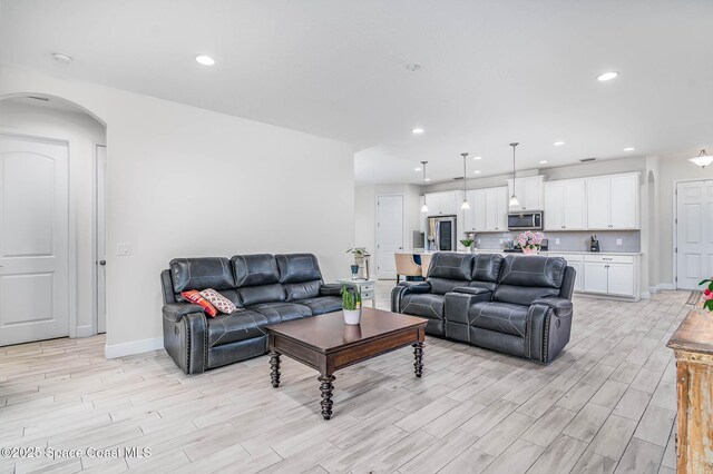 7921 Mocan Ct, Melbourne, FL 32940 - living room with light wood-style flooring, arched walkways, recessed lighting, and baseboards