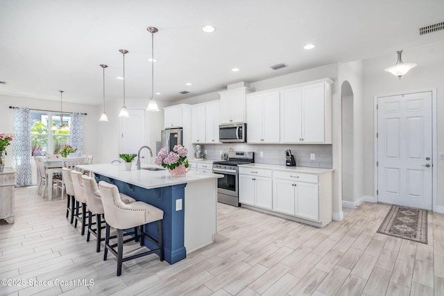 7921 Mocan Ct, Melbourne, FL 32940 - kitchen with appliances with stainless steel finishes, a breakfast bar area, tasteful backsplash, arched walkways, and a center island with sink