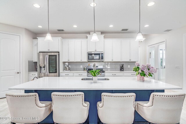 7921 Mocan Ct, Melbourne, FL 32940 - kitchen featuring appliances with stainless steel finishes, a center island with sink, backsplash, recessed lighting, and white cabinetry