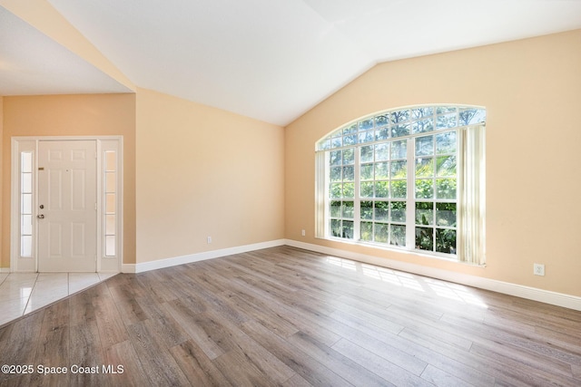 interior space with vaulted ceiling, baseboards, and wood finished floors