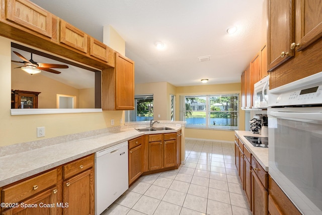 kitchen featuring a sink, white appliances, ceiling fan, light countertops, and light tile patterned floors