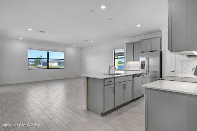 kitchen featuring appliances with stainless steel finishes, gray cabinets, decorative backsplash, and a sink