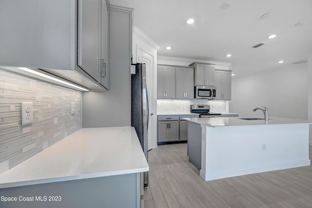 kitchen with a sink, decorative backsplash, gray cabinets, appliances with stainless steel finishes, and visible vents