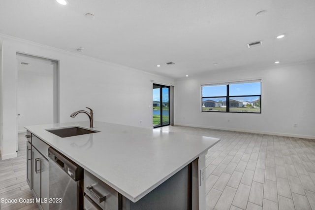 kitchen featuring dishwasher, light countertops, a sink, and an island with sink