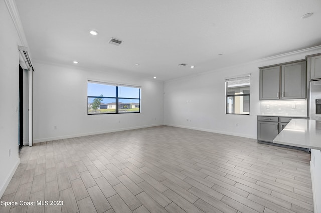 unfurnished living room with baseboards, visible vents, recessed lighting, light wood-style floors, and ornamental molding