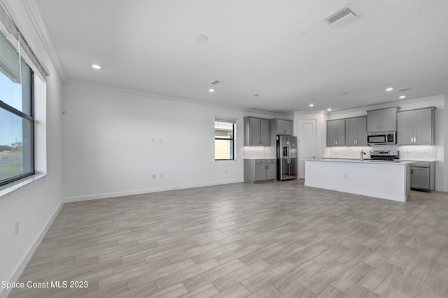kitchen with visible vents, gray cabinets, crown molding, appliances with stainless steel finishes, and open floor plan