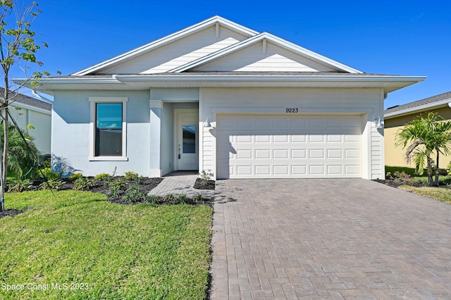 single story home featuring a garage, stucco siding, a front yard, and decorative driveway