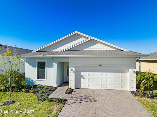 single story home with a garage, stucco siding, a shingled roof, and decorative driveway
