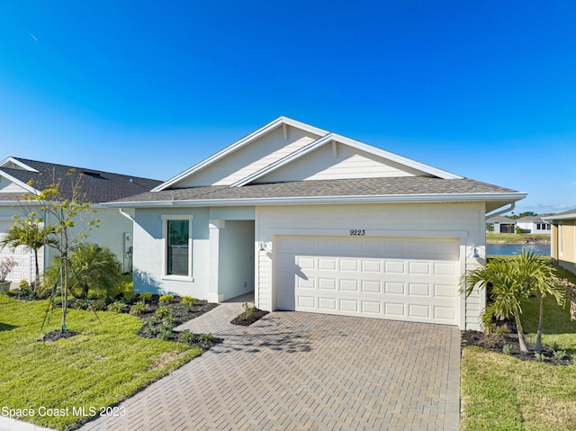 ranch-style house featuring an attached garage, a front yard, and decorative driveway