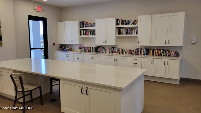 kitchen featuring white cabinets, a center island, open shelves, and light countertops