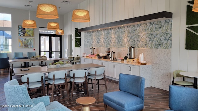 interior space featuring white cabinets, dark wood finished floors, a towering ceiling, light countertops, and visible vents