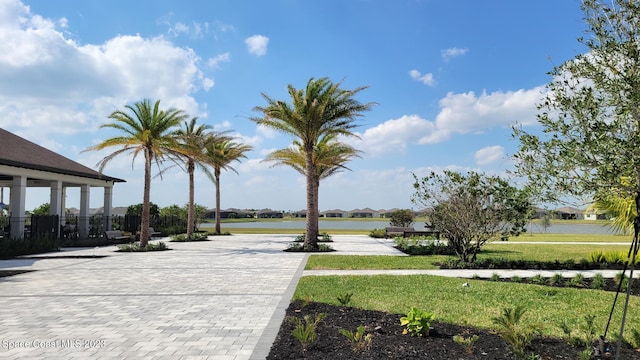 exterior space featuring fence, a lawn, and a water view