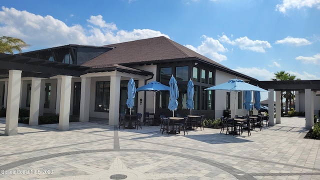 rear view of property featuring a patio area, a pergola, outdoor dining space, and stucco siding
