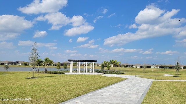 view of community with a pergola, a yard, a residential view, a water view, and a carport