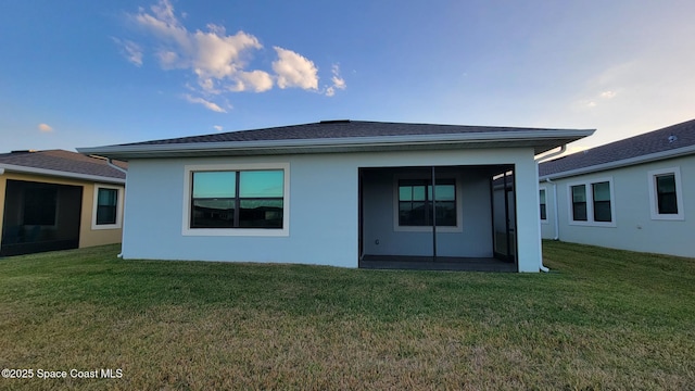 rear view of property with a lawn and stucco siding