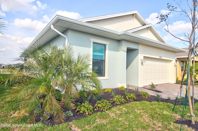 view of front of house with an attached garage, stucco siding, and driveway