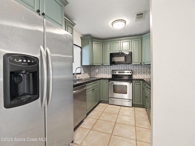 1640 Barna Ave, Titusville, FL 32780 - kitchen with green cabinetry, visible vents, a sink, tasteful backsplash, and appliances with stainless steel finishes
