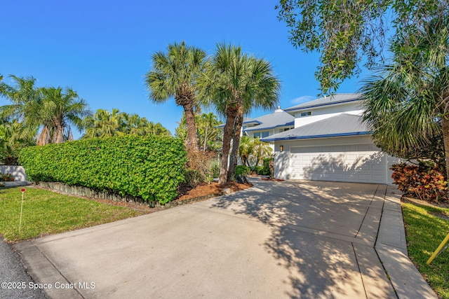 450 Ross Ave, Melbourne Beach, FL 32951 - view of front of property featuring a front yard, an attached garage, metal roof, and driveway
