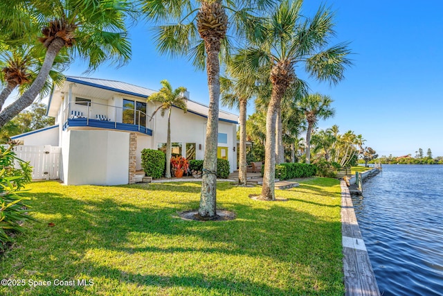 450 Ross Ave, Melbourne Beach, FL 32951 - view of front of property with a balcony, stucco siding, a front lawn, a water view, and fence