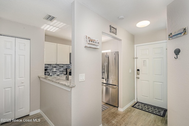 326 Seaport Blvd Unit T95, Cape Canaveral, FL 32920 - kitchen with stainless steel fridge with ice dispenser, light wood-style floors, white cabinets, backsplash, and light stone countertops
