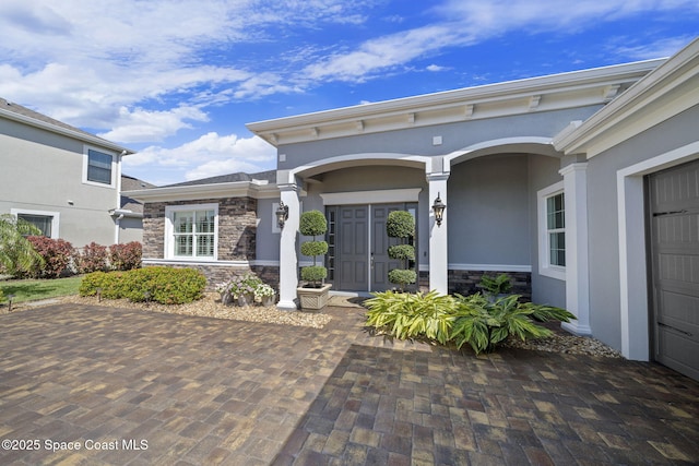 doorway to property with stone siding and stucco siding