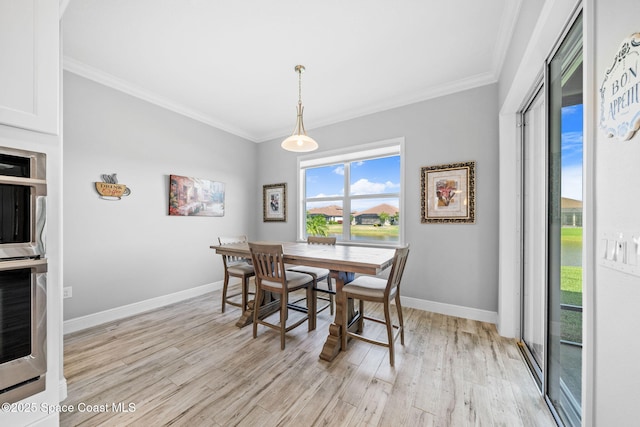 dining space featuring baseboards, light wood-style floors, and crown molding