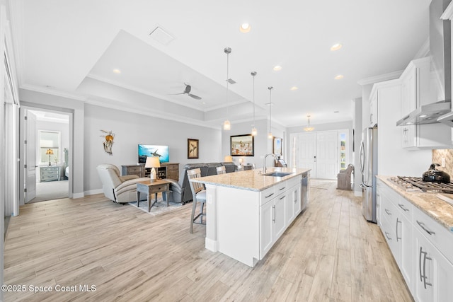 kitchen featuring stainless steel appliances, a kitchen breakfast bar, a sink, open floor plan, and visible vents