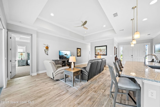 living area featuring a raised ceiling, visible vents, light wood finished floors, and a wealth of natural light