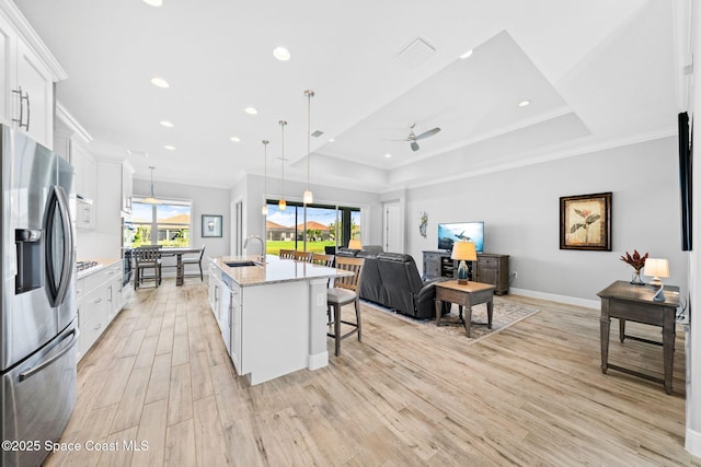 kitchen featuring stainless steel fridge with ice dispenser, a sink, light wood-type flooring, crown molding, and white cabinetry