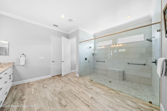 full bathroom with a shower stall, wood finished floors, vanity, ornamental molding, and baseboards