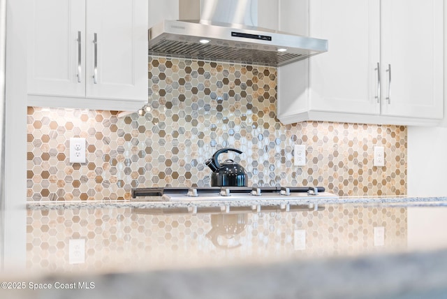 kitchen featuring white cabinets, decorative backsplash, and wall chimney range hood