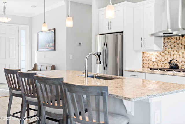 kitchen with a sink, decorative backsplash, stainless steel appliances, wall chimney exhaust hood, and white cabinetry