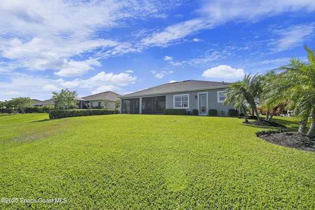 back of property featuring a yard, a sunroom, and stucco siding