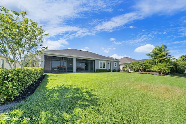 back of house with a lawn, a sunroom, and stucco siding
