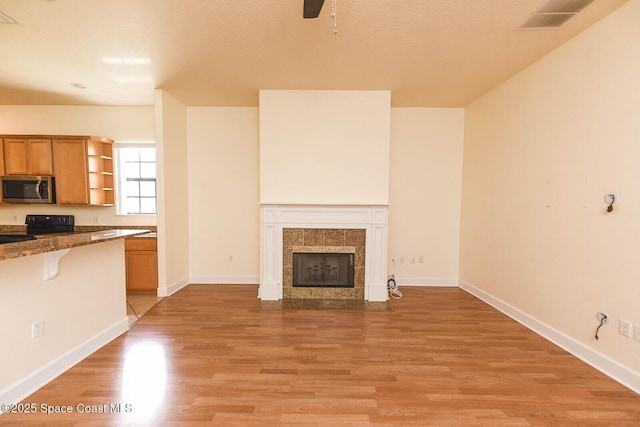 4068 Gardenwood Cir, Grant, FL 32949 - unfurnished living room with light wood-style floors, a ceiling fan, baseboards, and a tile fireplace