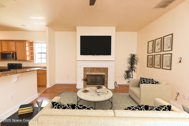 4068 Gardenwood Cir, Grant, FL 32949 - living room with a tile fireplace, light wood finished floors, a ceiling fan, and baseboards