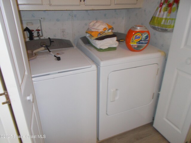 7637 Nianntic Ave Unit T5, Micco, FL 32976 - laundry area featuring light wood-type flooring, wallpapered walls, washing machine and clothes dryer, and cabinet space