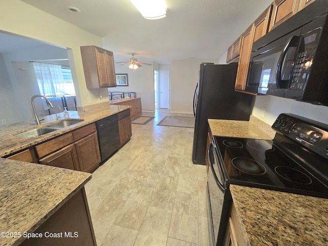 kitchen with a sink, a ceiling fan, brown cabinets, black appliances, and light stone countertops