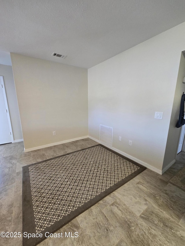 empty room featuring baseboards, visible vents, and a textured ceiling