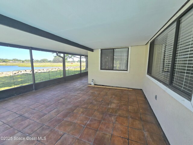 unfurnished sunroom with tile patterned floors and a water view